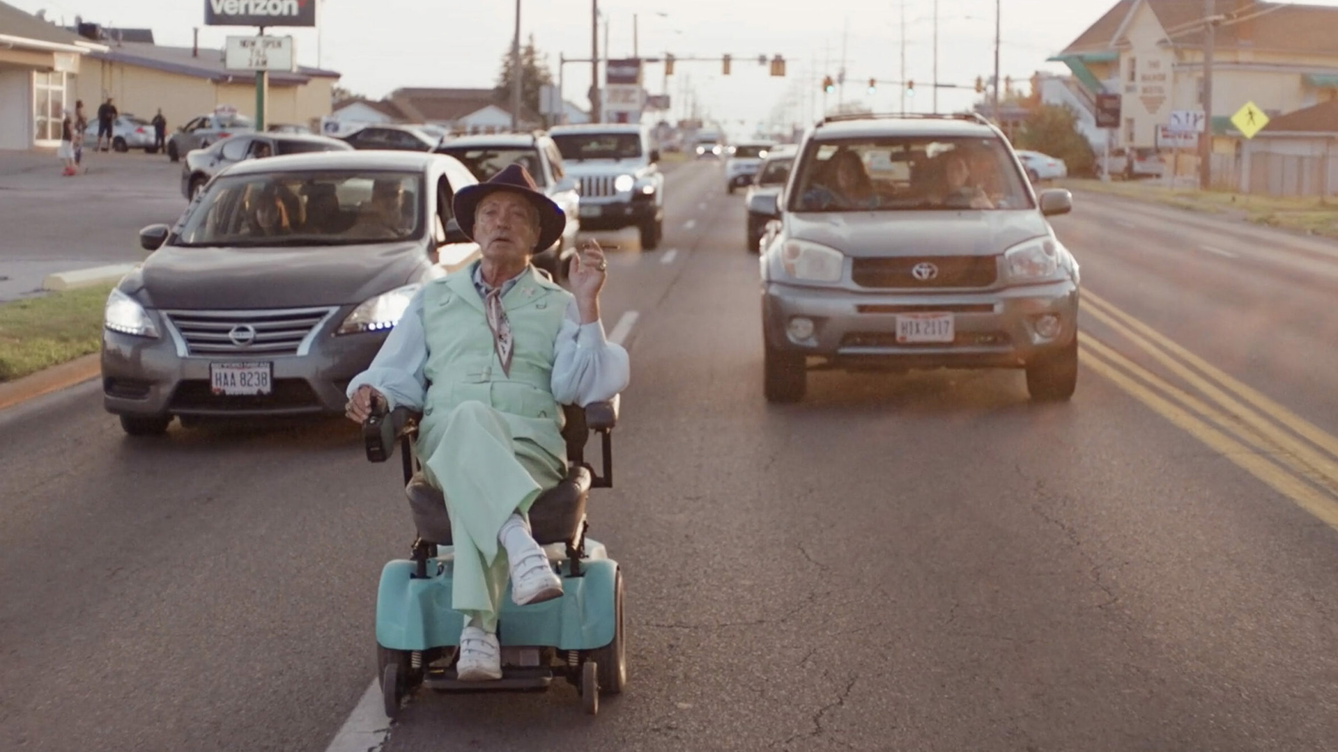 Trailer still frame from Swan Song, man on road in electric wheelchair