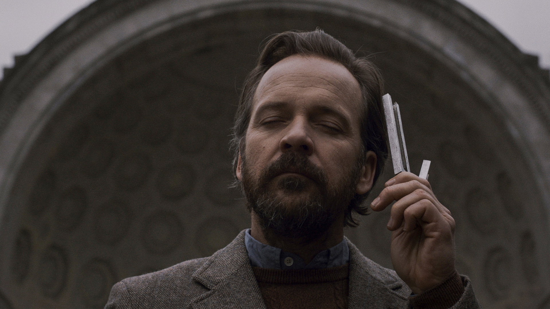 Trailer still frame from The Sound of Silence, man holding tuning fork