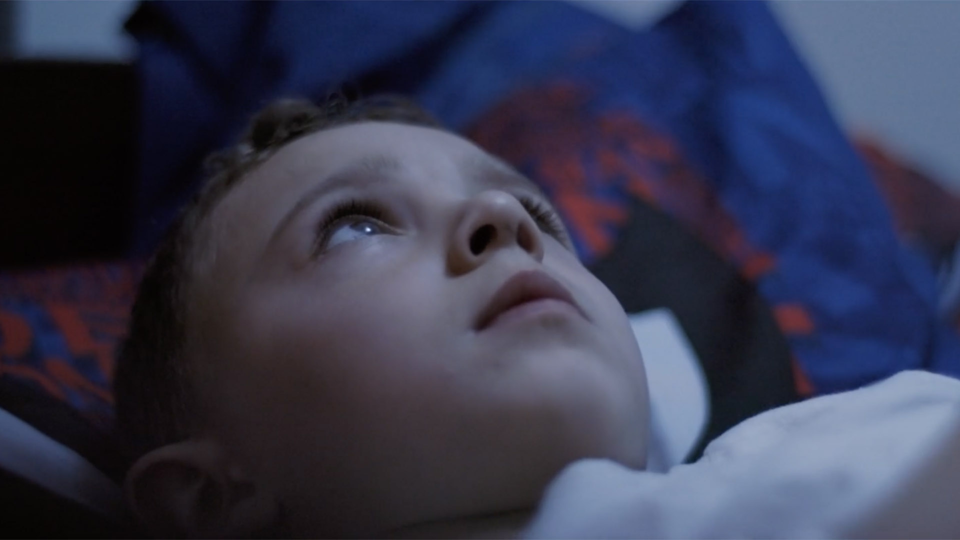 Trailer still frame from Something Left Behind, young boy in bed