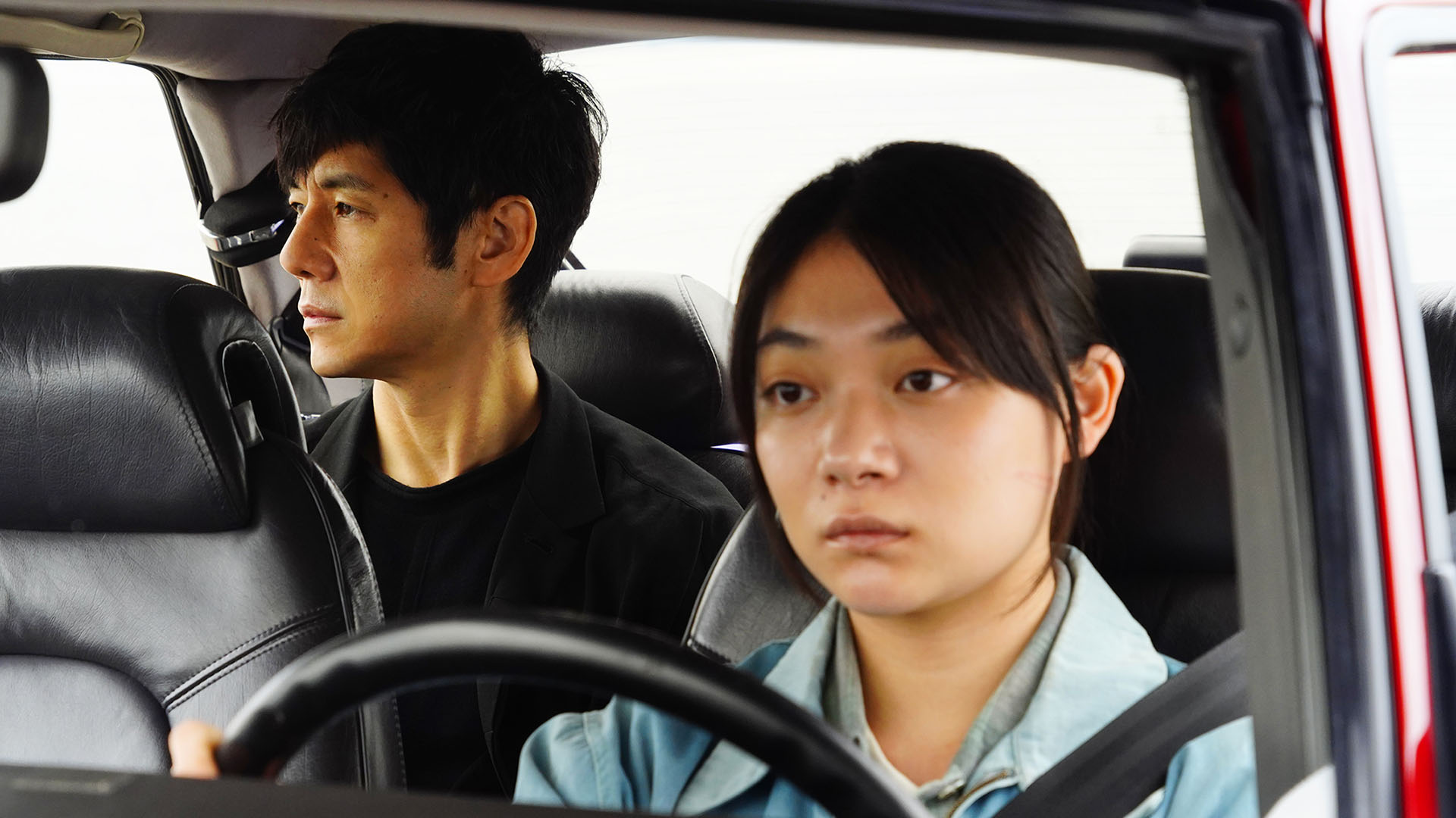 Trailer still frame from Drive My Car, woman driving car with man in backseat