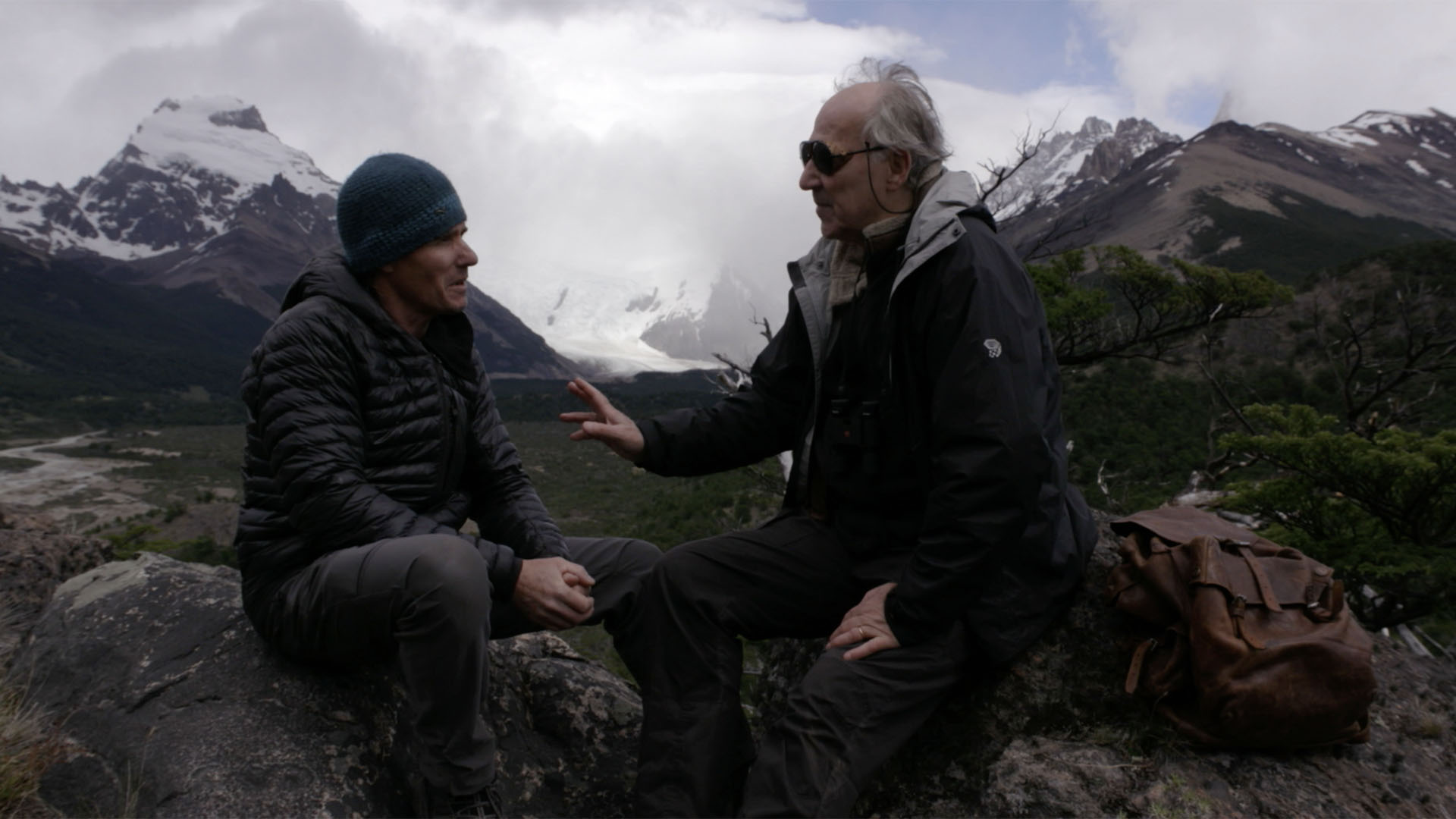 Trailer still frame from Nomad, two men talking at mountains