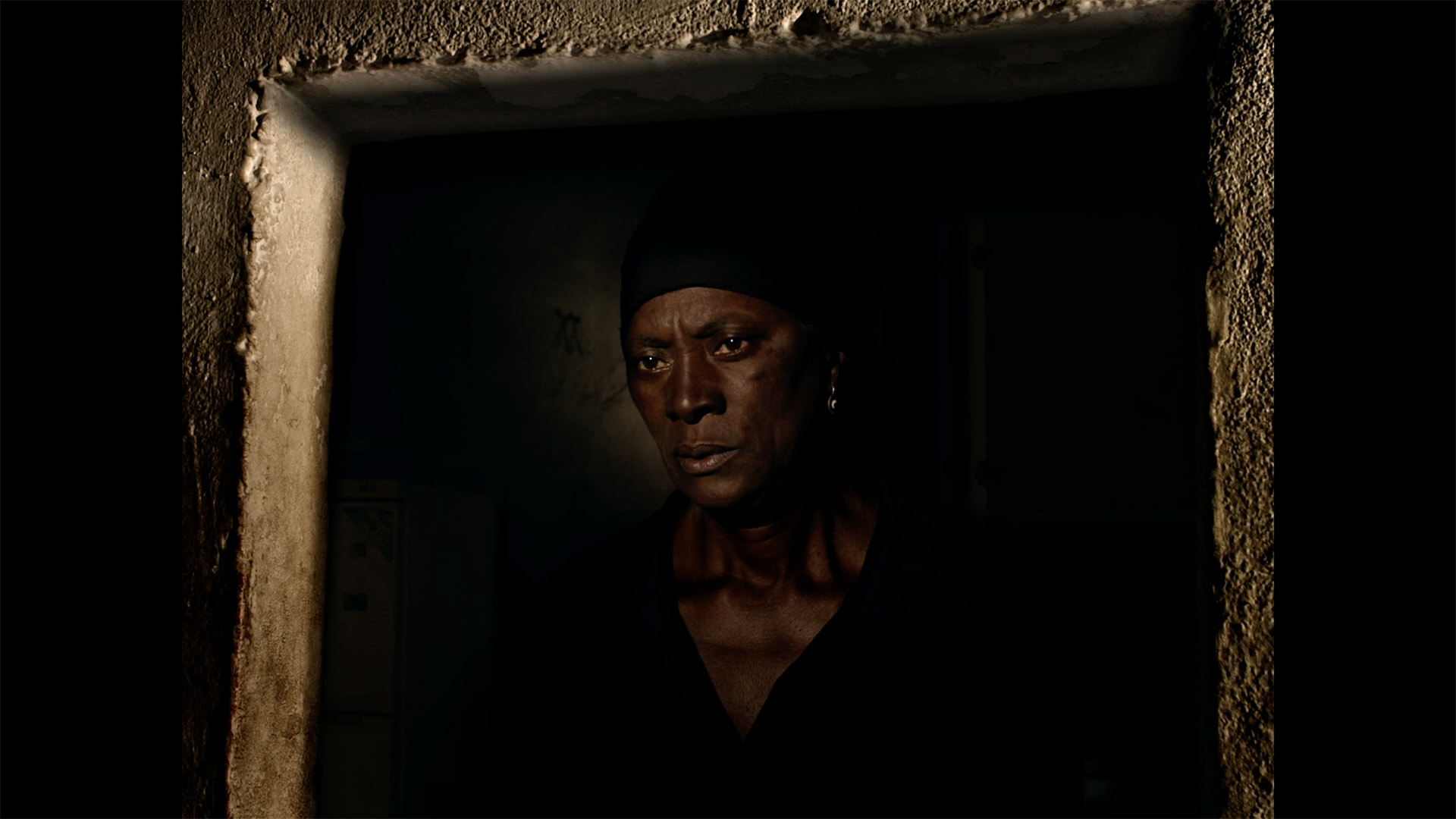 Trailer still frame from Vitalina Varela, woman in doorway