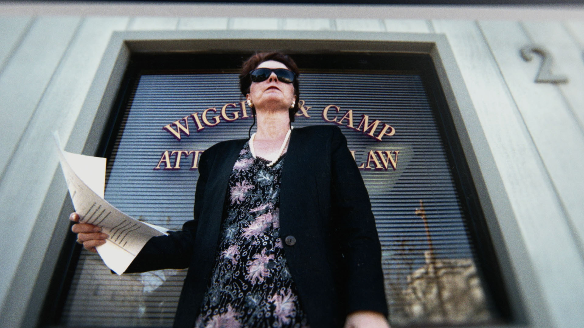 Trailer still frame from Children of the Underground, woman holding paper in front of attorney office